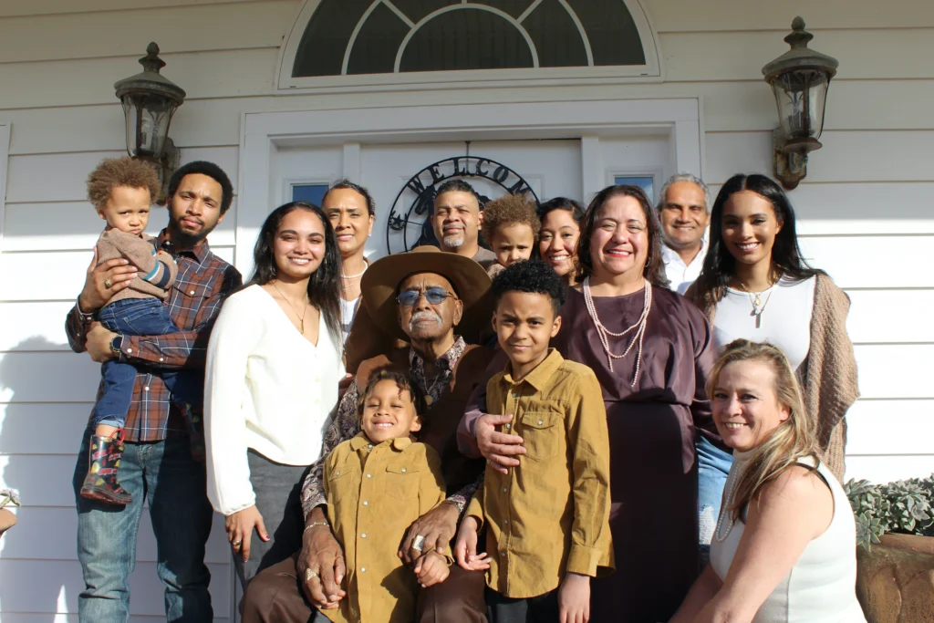 A multigenerational, diverse family gathered together outside a home, smiling